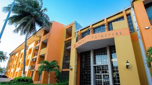 A hotel with a yellow facade, balconies, and a palm tree. - Hotel Palmarena Plaza (Santa Marta)