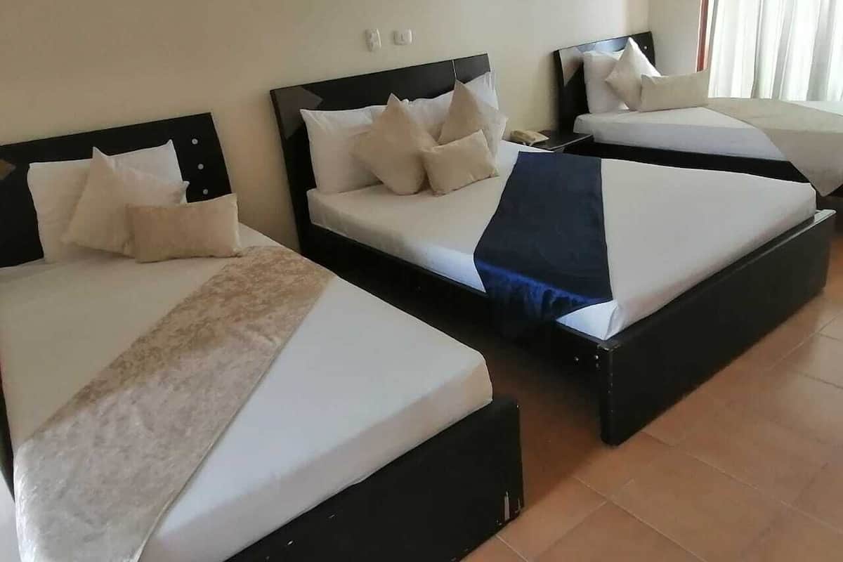 Three single beds with headboards, a bedside table, and a nightstand.