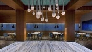 A spacious room with a marble floor, wooden paneling, and hanging light fixtures. - Al Jasra Boutique Hotel (Doha)