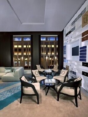 A modern living room with a sofa, armchairs, and a coffee table. There is a large window with a view of the city. - Al Jasra Boutique Hotel (Doha)