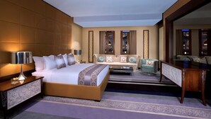 A spacious hotel room with a large bed, a sofa, a desk, and a mirror. - Al Jasra Boutique Hotel (Doha)