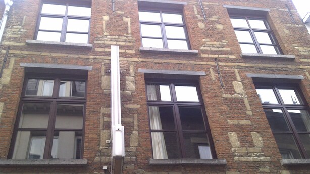 Ein mehrgeschossiges Backsteinhaus mit großen Fenstern und einer zentralen vertikalen Struktur.