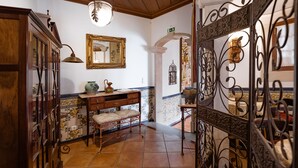 A traditional interior with a wooden ceiling, a mirror, a bench, and a decorative gate. - Casa de Sao Thiago d' Obidos (Obidos)