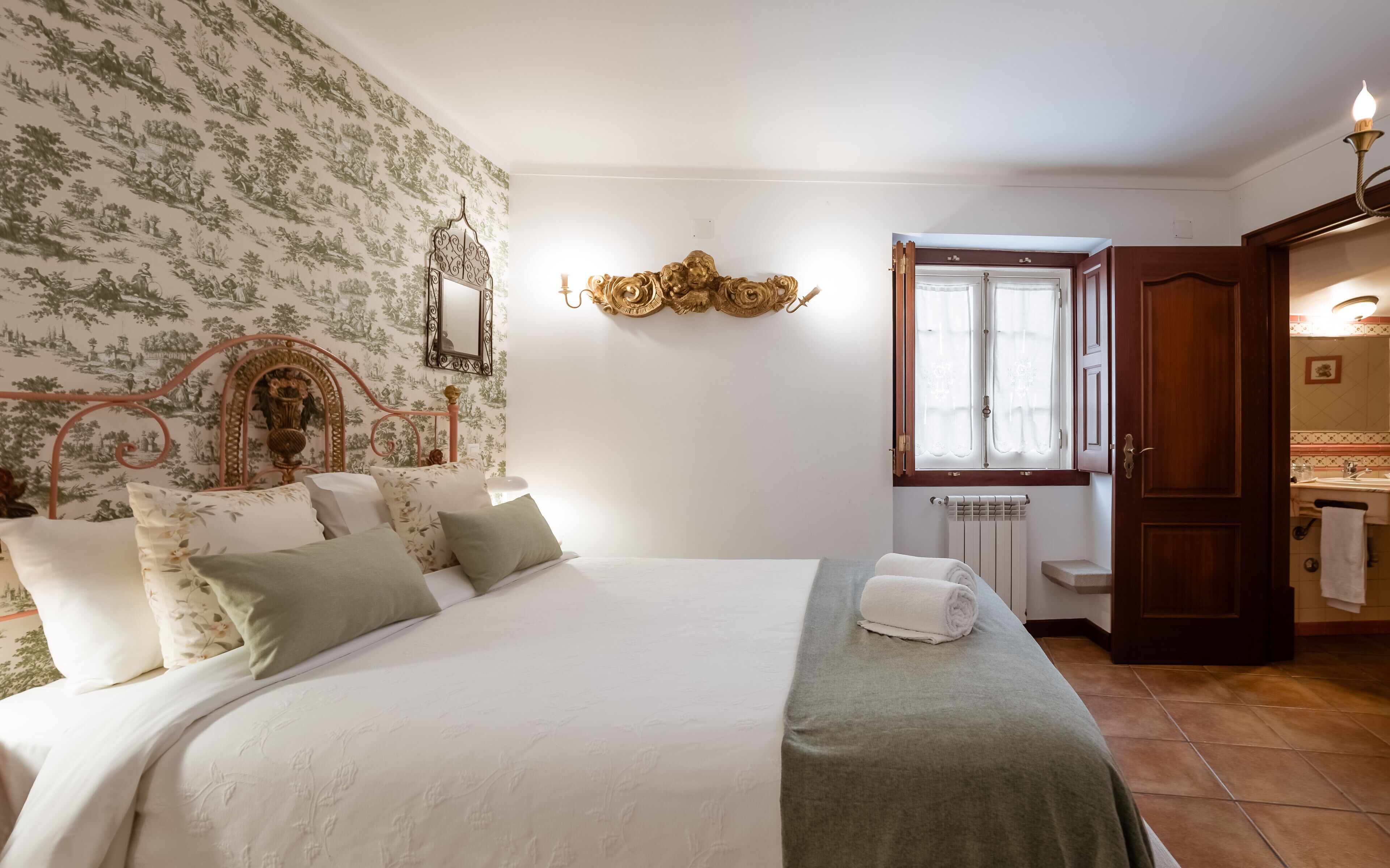 Un dormitorio con cama, espejo, radiador y puerta que da a un baño.