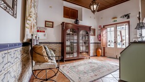 A traditional interior with a wooden cabinet, a tiled floor, and a patterned rug. - Casa de Sao Thiago d' Obidos (Obidos)