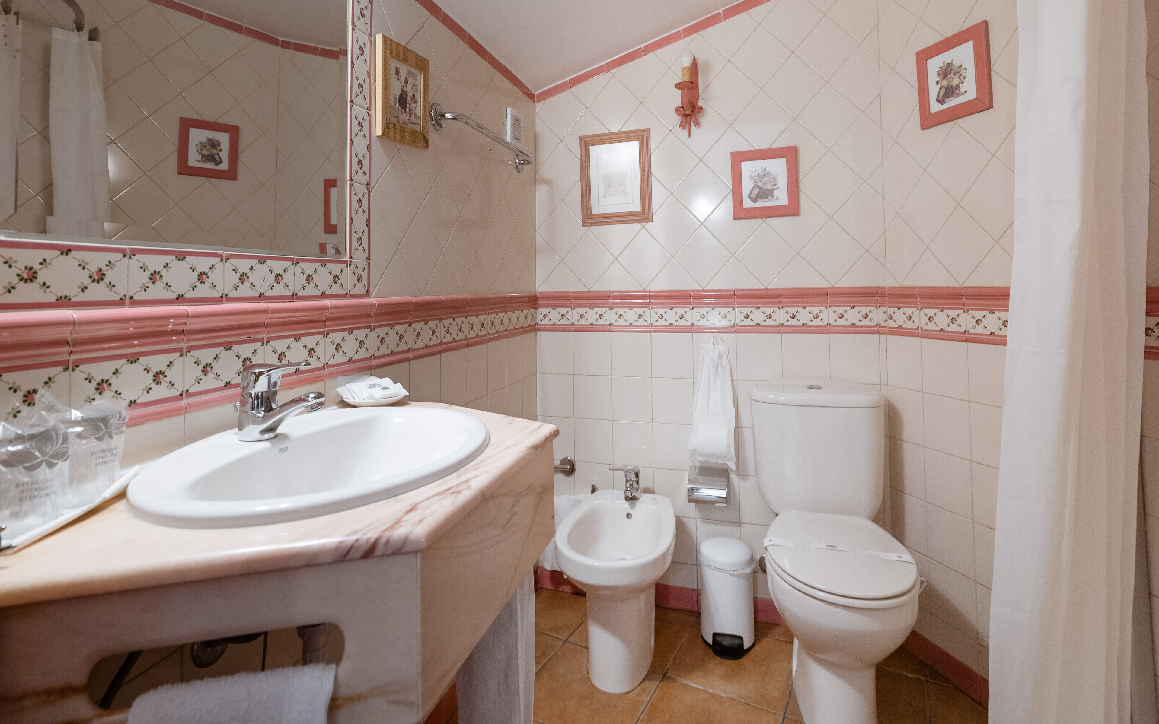 A bathroom with a sink, bidet, and toilet.