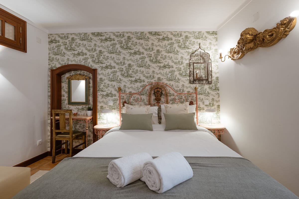 Ein ordentlich eingerichtetes Schlafzimmer mit Bett, Nachttischen, einem Stuhl und einem Spiegel.