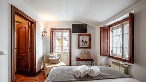 A bedroom with a bed, a chair, a TV, a window, and a door. - Casa de Sao Thiago d' Obidos (Obidos)