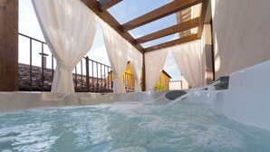 A hot tub with a wooden ceiling and white curtains, surrounded by a stone-tiled roof and a metal railing. - Di Sabatino Resort (Ascoli Piceno)