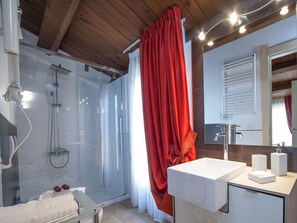 A modern bathroom with a glass-enclosed shower, a white sink, and a red curtain.