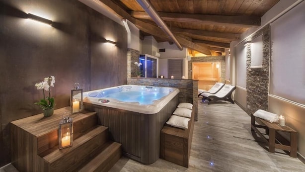 A spa area with a hot tub, wooden steps, and lounge chairs. - Di Sabatino Resort (Ascoli Piceno)