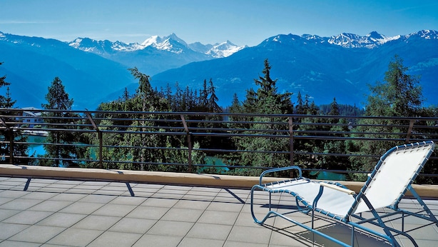 A balcony with a chair overlooking a mountain range. - Youth Hostel Crans-Montana (Crans-Montana)