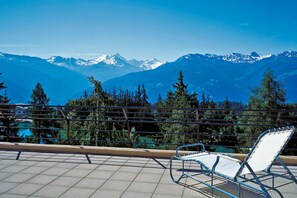 Un balcon avec une chaise donnant sur une chaîne de montagnes.