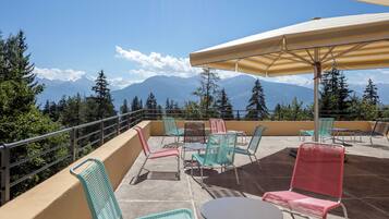 Eine Terrasse mit Außenbestuhlung, einem Tisch und einem großen Sonnenschirm.
