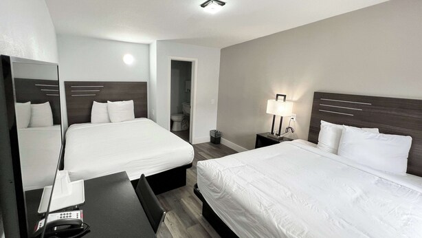 Une chambre d’hôtel avec deux lits, un bureau, une lampe et un miroir.