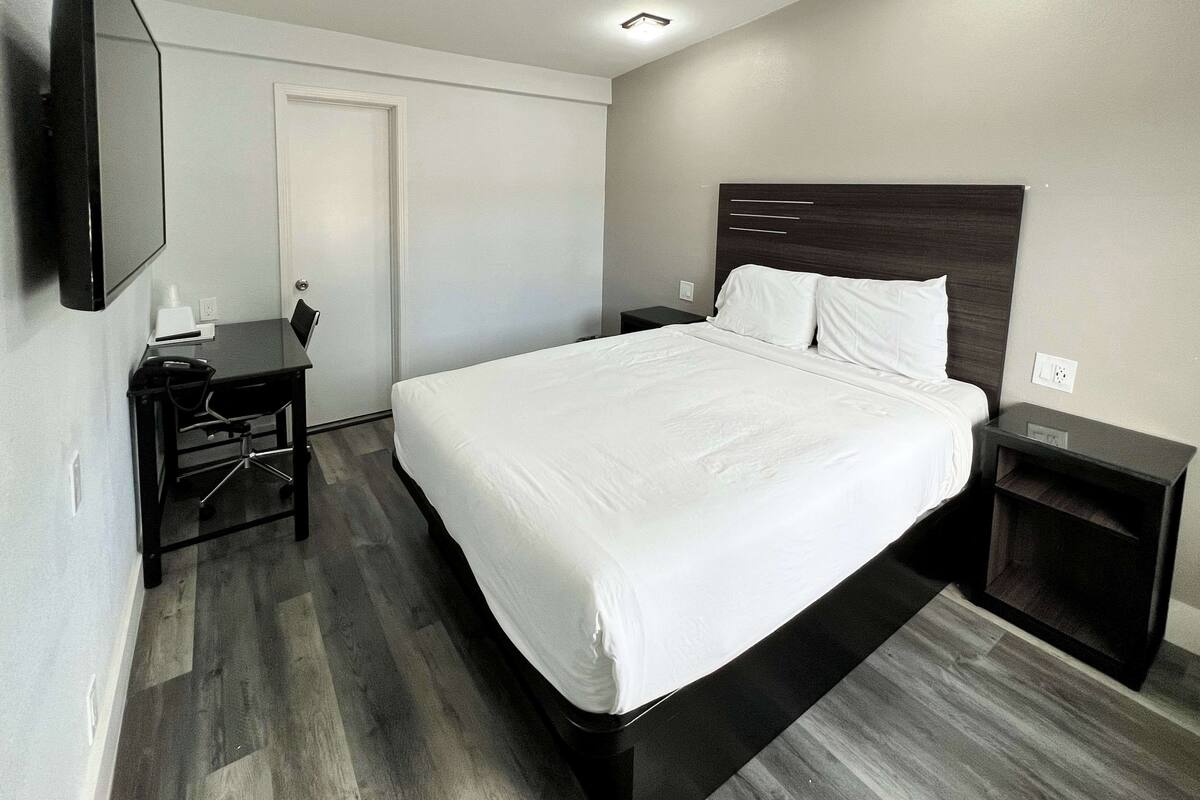 A modern hotel room with a large bed, a desk, and a flat-screen TV.