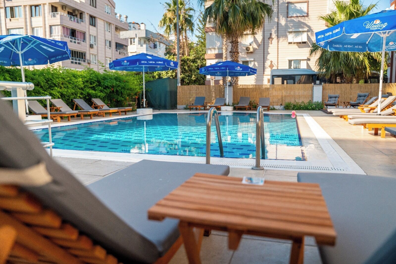 A pool area with lounge chairs and umbrellas, surrounded by buildings.