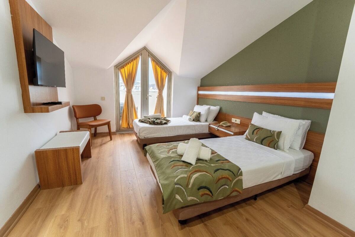 Een hotelkamer met een bed, een bureau, een stoel, een televisie en een raam met gordijnen.