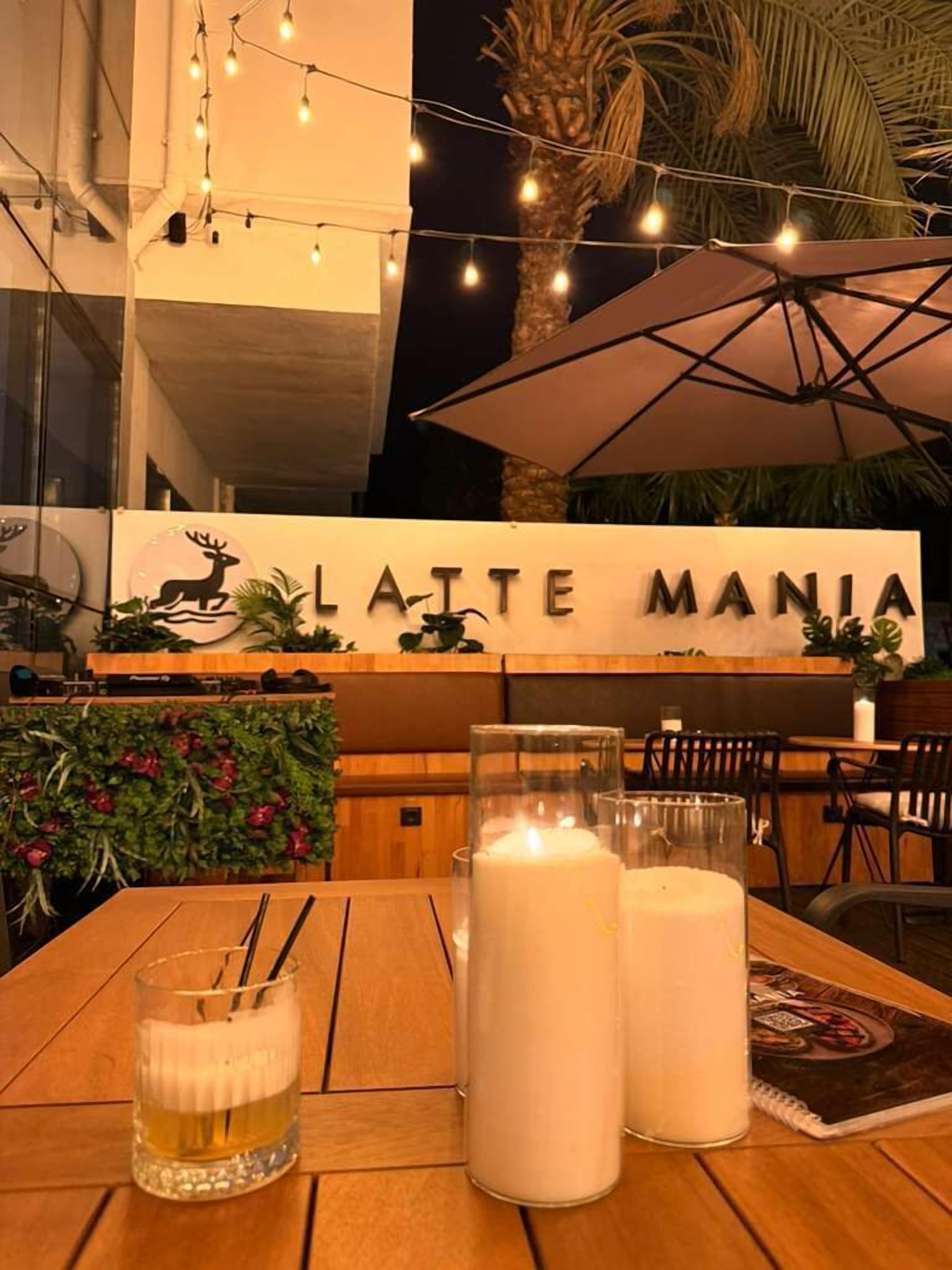 A table with a glass of beer, two candles, and a notebook at a restaurant named 'LAITE MANIA'.