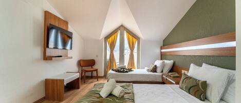 A bedroom with a bed, a desk, a chair, a TV, and a window with curtains.