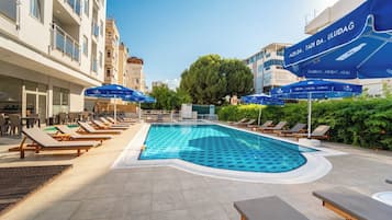 Una piscina al aire libre de temporada, sombrillas