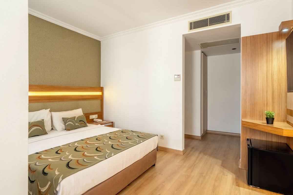 Een hotelkamer met een bed, nachtkastje en een inbouwkast.