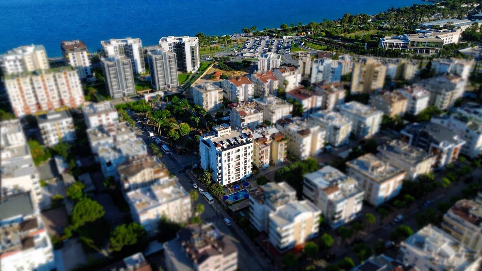 An aerial view of a coastal urban area with high-rise buildings, a marina, and a road network.