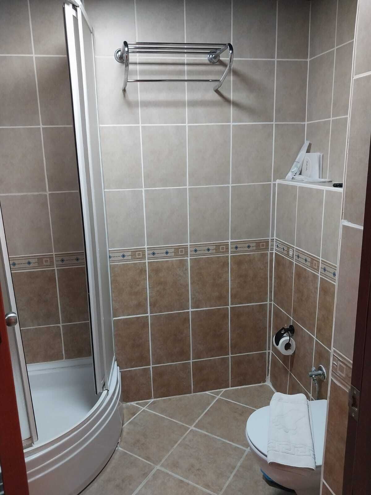 Un baño con ducha, inodoro y perchero para toallas.