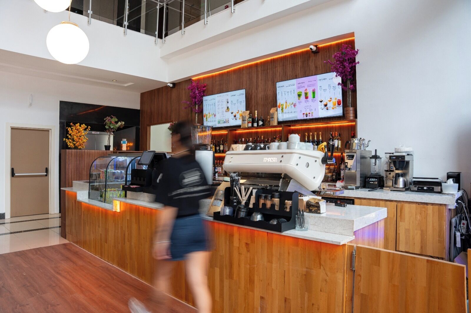Eine moderne Bar mit einer Kaffeemaschine, einer Speisekarte und einer Holztresen.