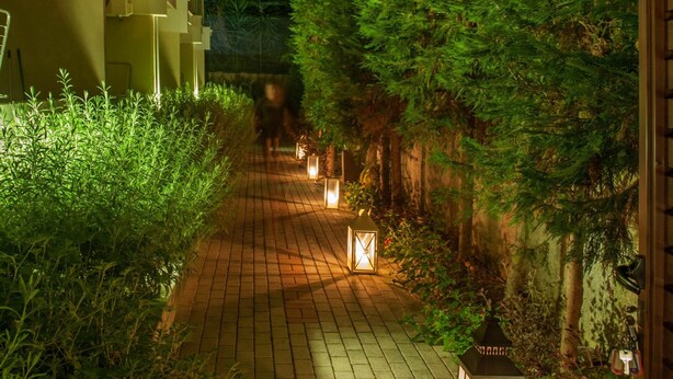 A nighttime pathway with lanterns, a building with balconies, and dense greenery. - Hotel Galaxias (Rhodes)