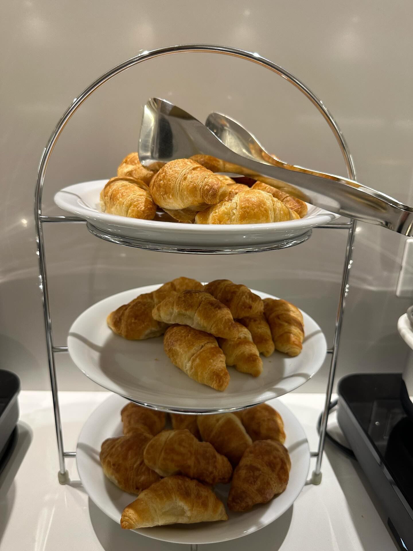 A three-tiered serving stand with plates of croissants.