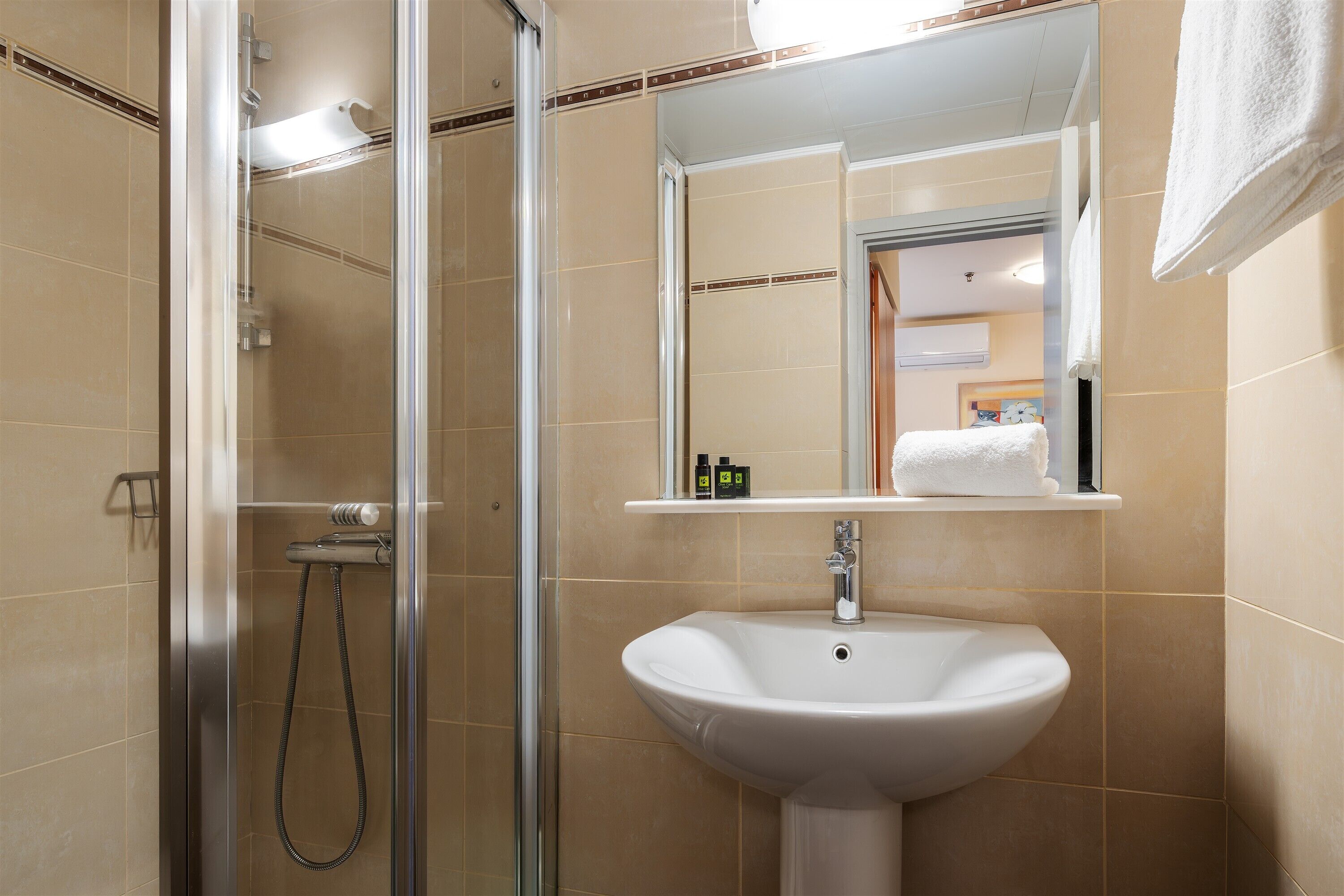 A modern bathroom with a glass-enclosed shower, a white sink, and a mirror above the sink.