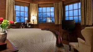 Una habitación acogedora con una cama grande, televisión y una ventana con cortinas.