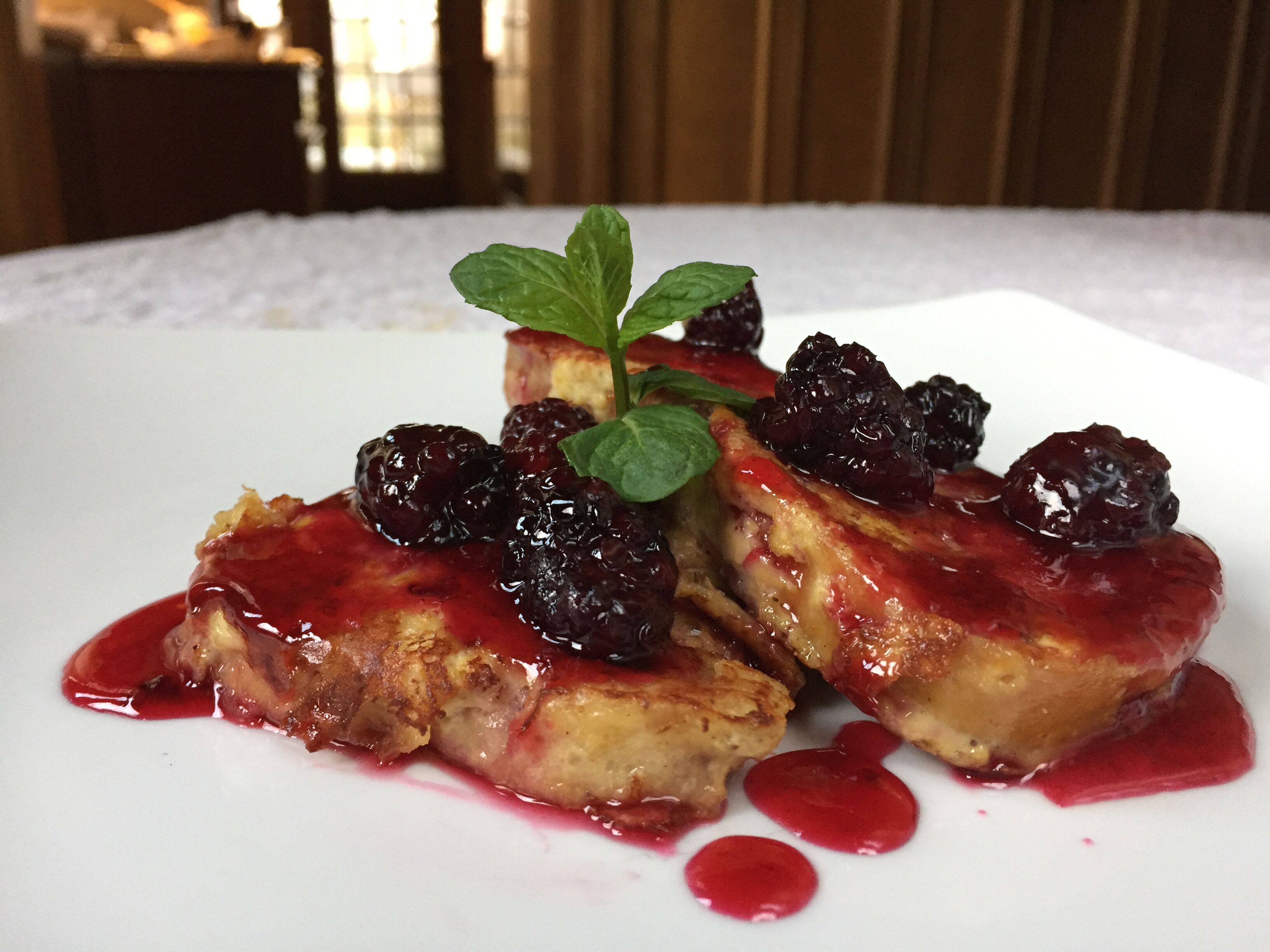 A dessert with berries and mint on a white plate.
