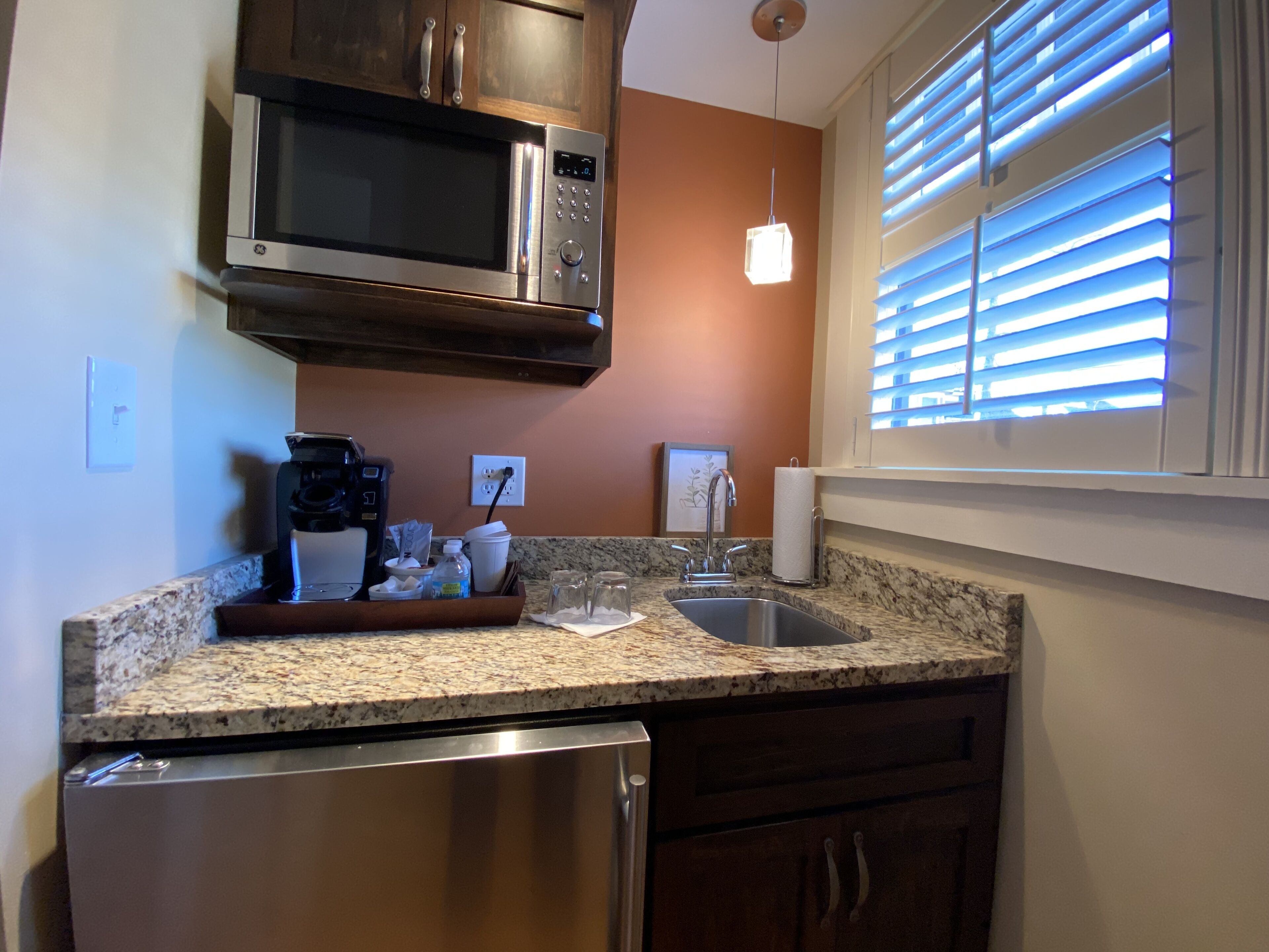 A kitchen with a built-in microwave, coffee maker, and stainless steel refrigerator.