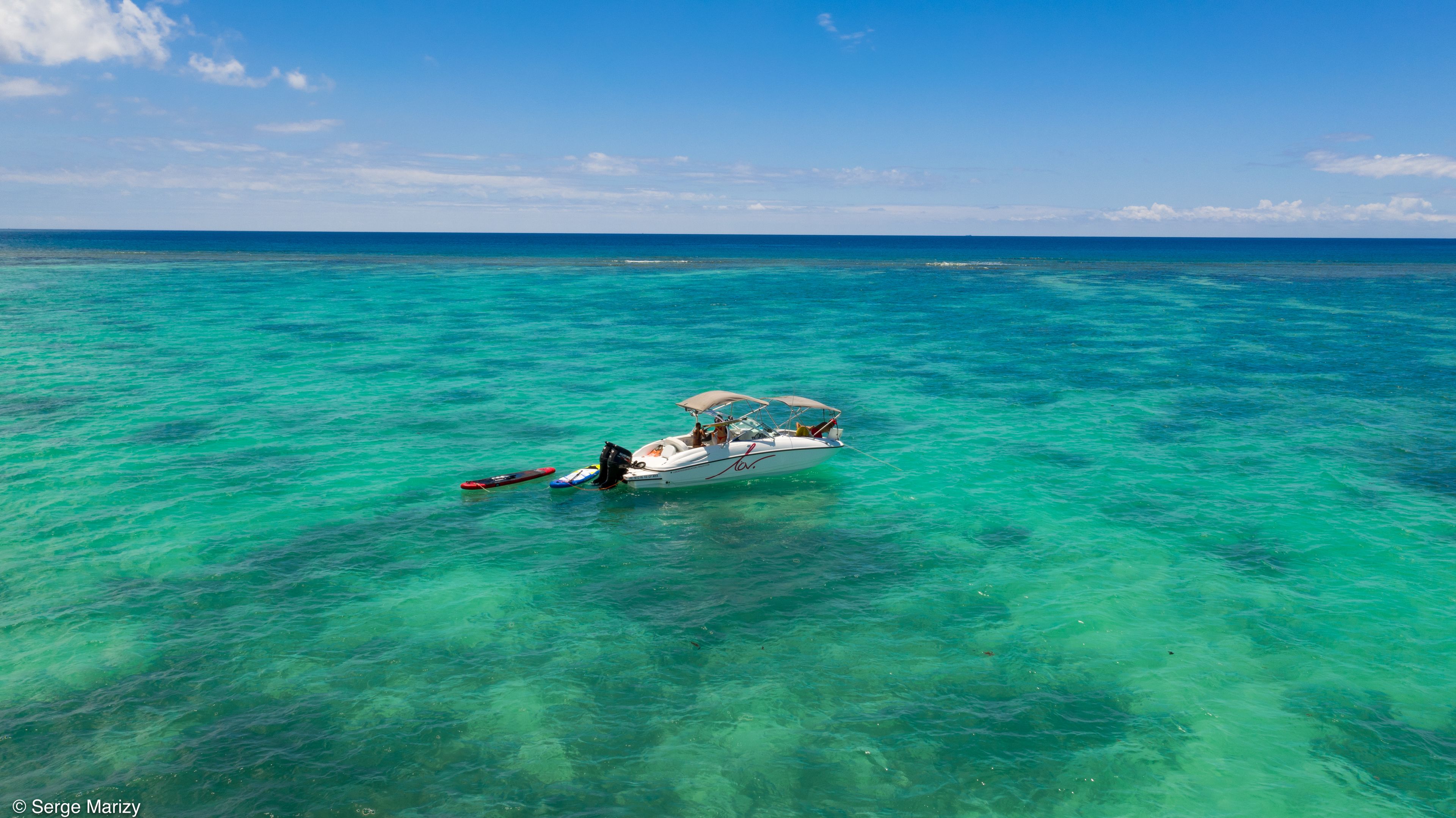 A boat on clear turquoise water with a clear sky.