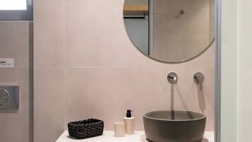 Un baño moderno con un espejo redondo, un lavabo y un perchero para toallas.