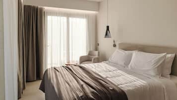 A modern hotel room with a large bed, a chair, and a pendant light.