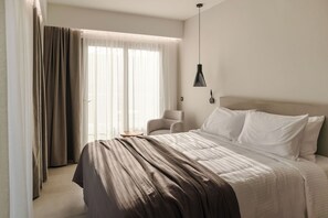 A modern hotel room with a large bed, a chair, and a pendant light.