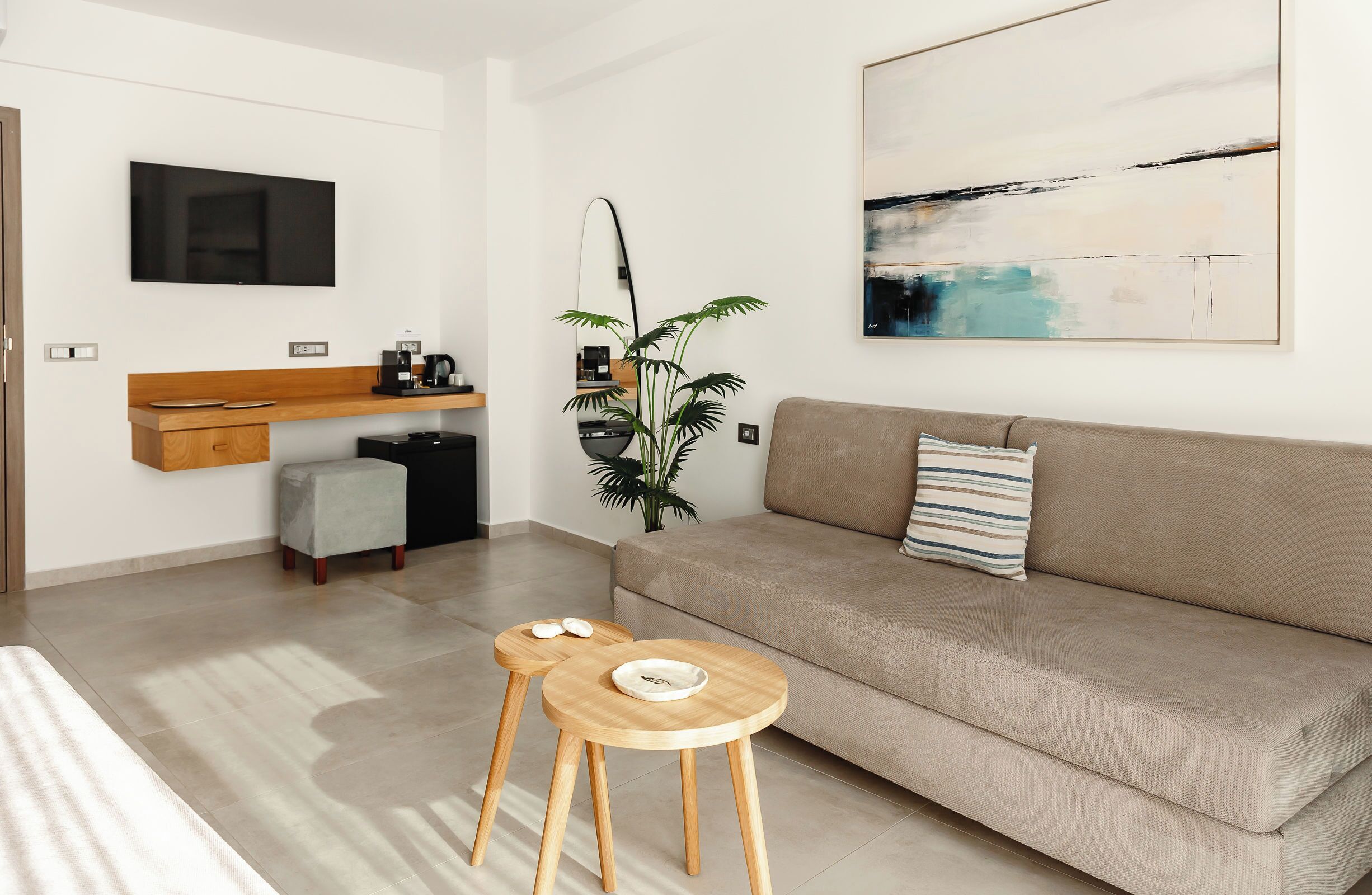 A modern living room with a sofa, a coffee station, a TV, and a plant.