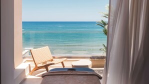 Una habitación con una cama, una silla y vista al océano.
