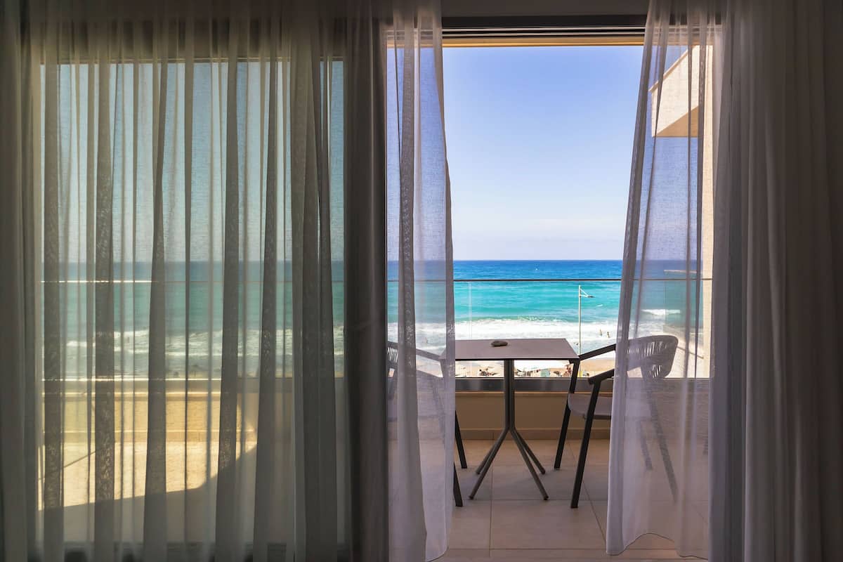 Un balcón con mesa y sillas que da a una playa.