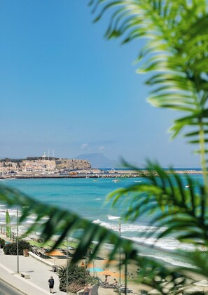 A coastal cityscape with a prominent fort, a promenade, and a beach area.
