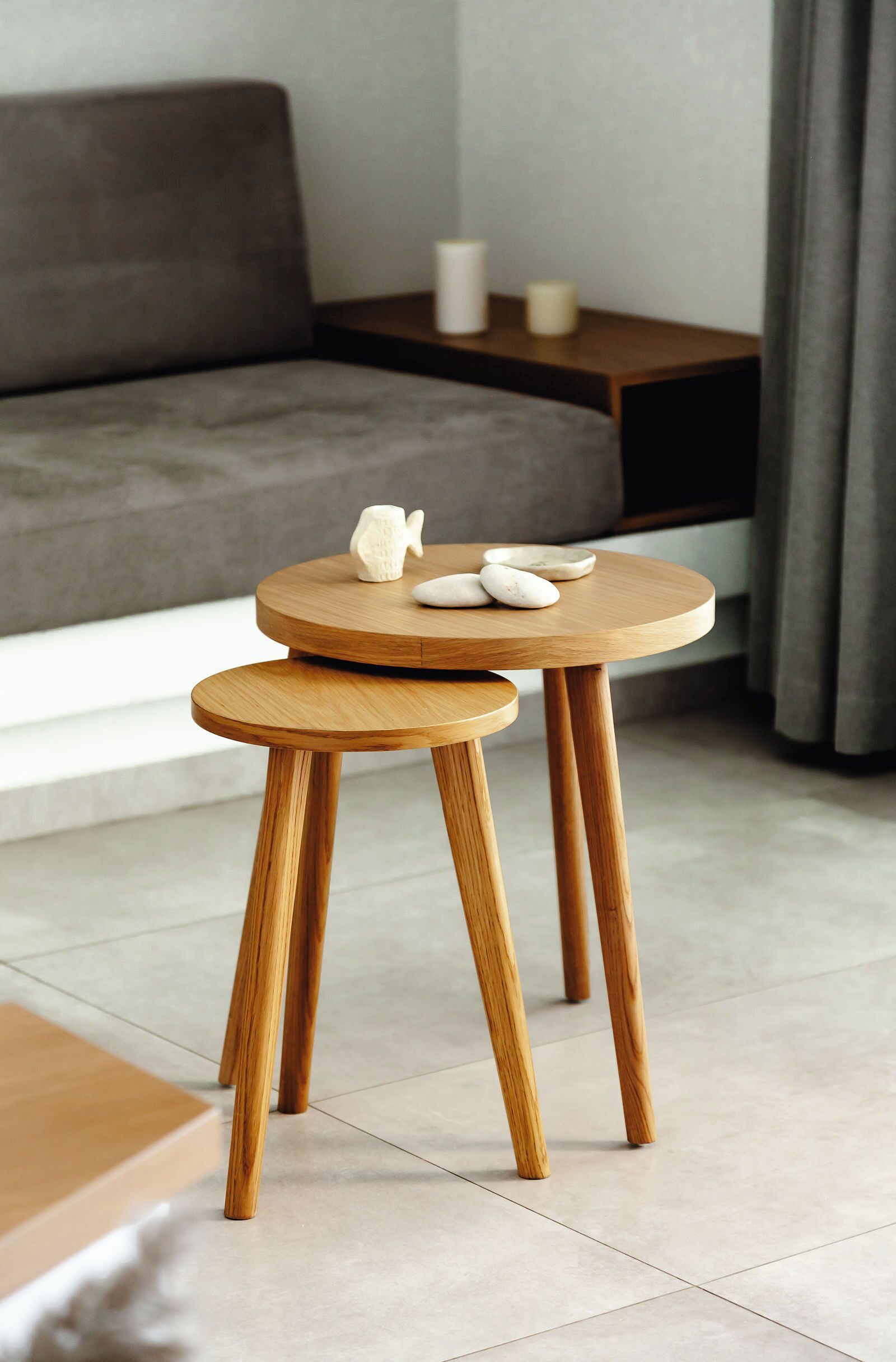 A modern room with a sofa, a small wooden table with a decorative item, and a candle on a side table.