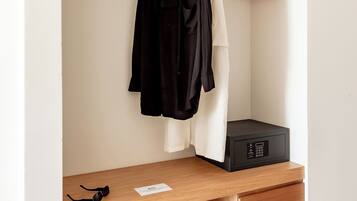 Un armario minimalista con estantes de madera, una percha y un dispositivo electrónico negro en el estante inferior.