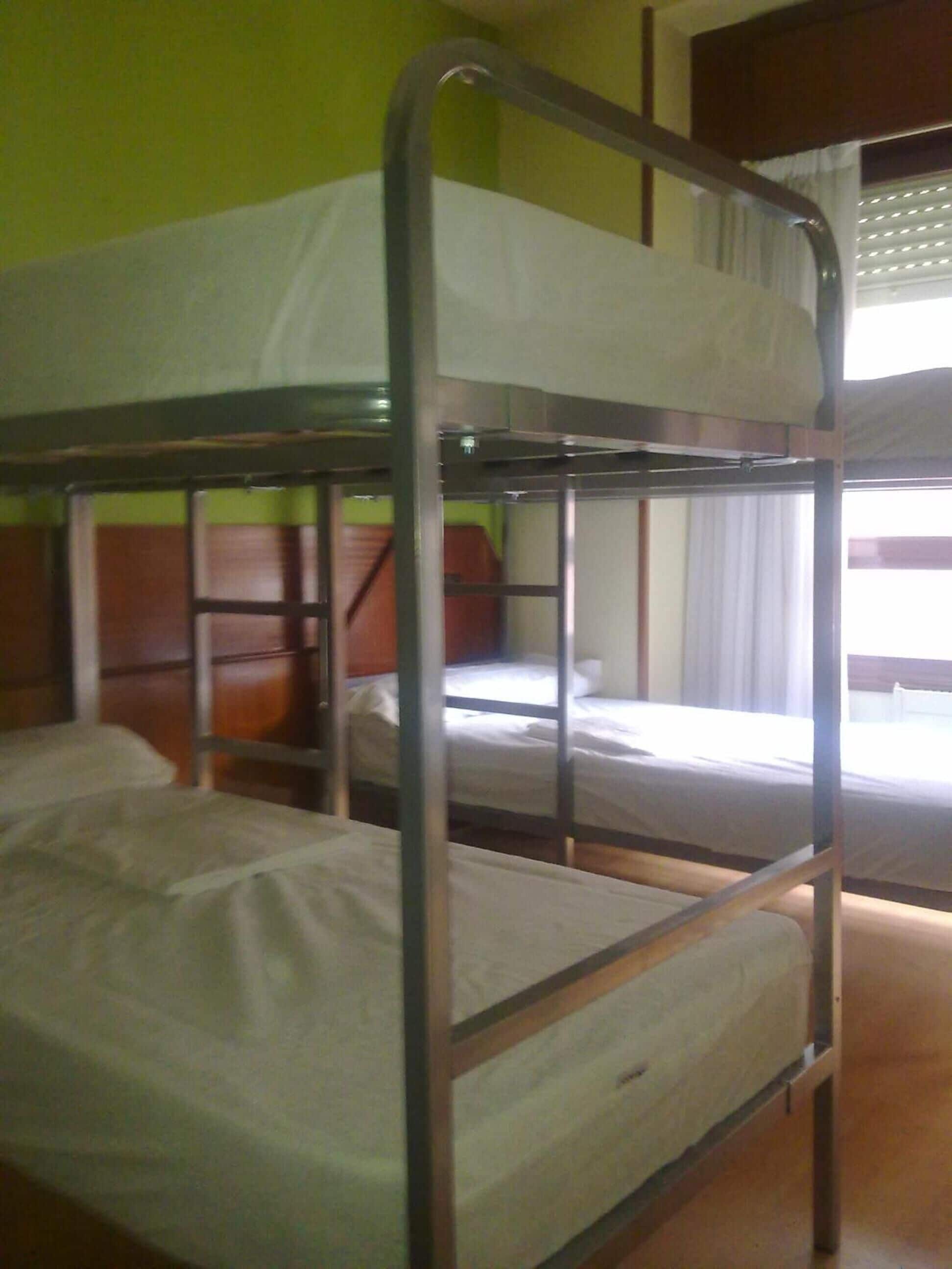 Habitación con literas, pared verde y ventana con cortinas.