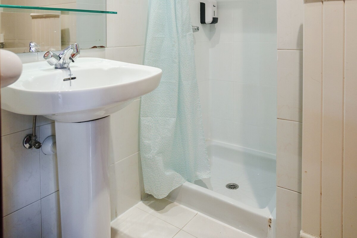 A bathroom with a white sink, a glass shower enclosure, and a white bathtub.