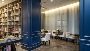 A modern library with bookshelves, a reading area with chairs and tables, and a blue accent wall. - Hotel Indigo Tel Aviv - Diamond District by IHG (Ramat Gan)