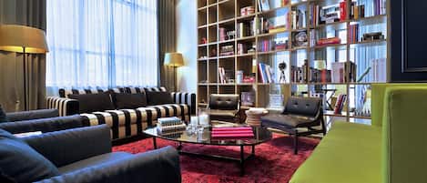 A modern living room with a striped sofa, a coffee table with books and a candle, and a bookshelf filled with books.