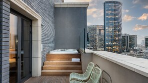 Una terraza en la azotea con un jacuzzi, escalones de madera y vistas de la ciudad.